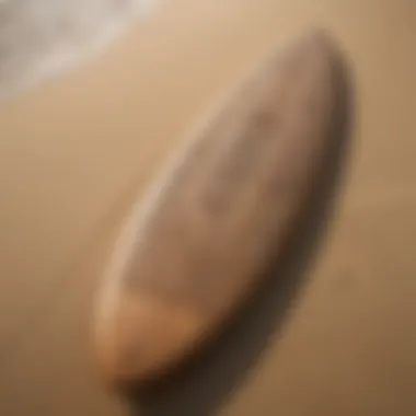 Close-up of a surfboard with Tahitian motifs resting on the sand