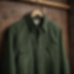 A vintage green corduroy button-up shirt displayed on a wooden hanger